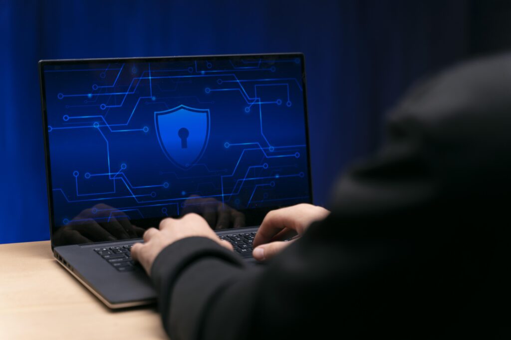 Pessoa tentando acessar um ambiente criptografado de um computador. A pessoa está de casaco e a tela do computador possui um cadeado, representando a segurança cibernética