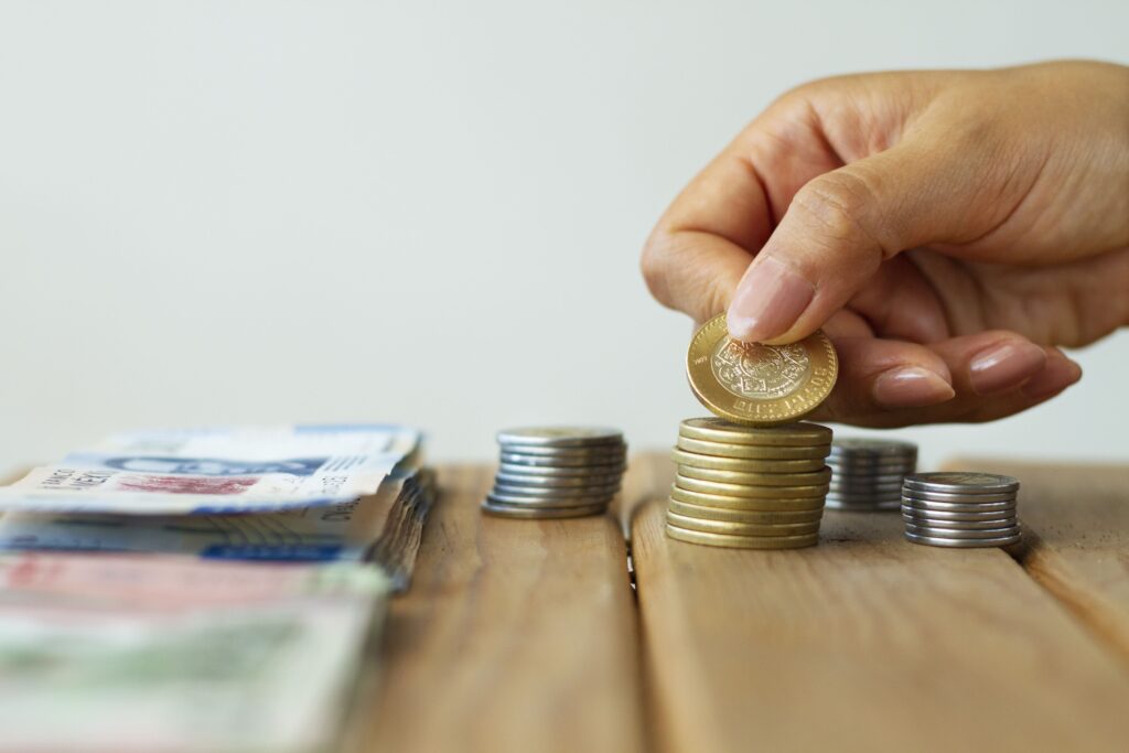 Pessoa contando moedas e notas, representando a economia e redução de custos