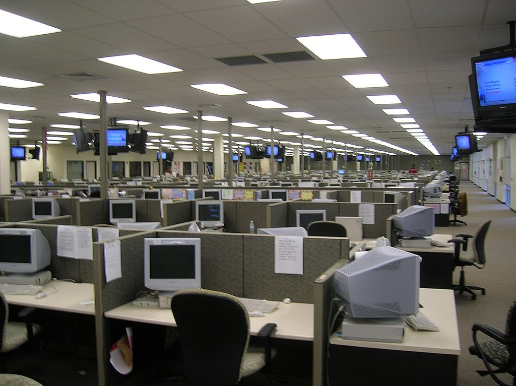Imagem interna de um call center, em sua sala de operações. Vários box para cada funcionário atendente.